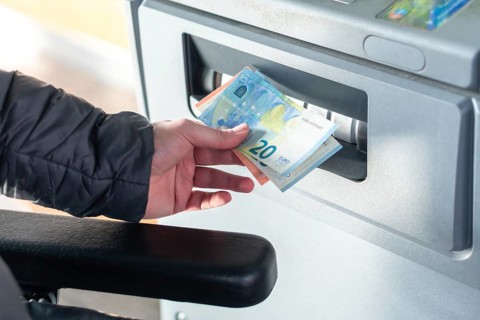 Close up photo of man taking cash, euros from ATM