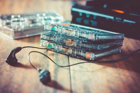 Closeup of cassette tape, tape player and headphones on wooden background