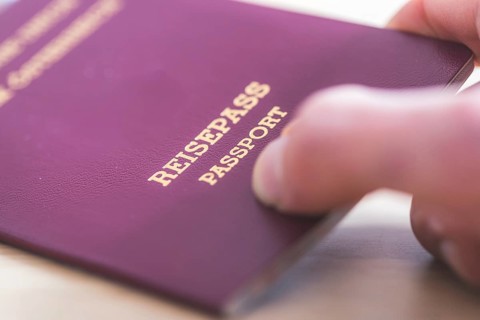 Close up of fingers holding a passport for travelling, airport, ?Reisepass Passport?