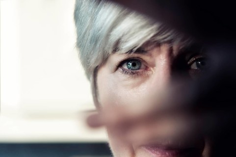 A woman looks through the fingers of her hand
