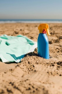 Close up blanket sunscreen cream blue bottle sand beach