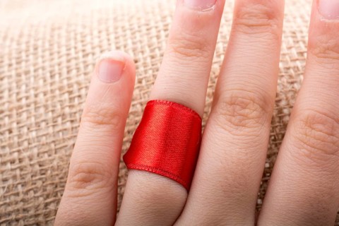 Red string tied around ring finger of the hand