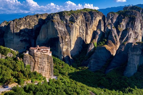 View of Meteora valley, Greece at midday. Clifftop Moni Agias Varvaras Roussanou nunnery among
