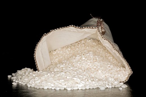 Spanish paella rice, of the Bomba variety, in a cotton bag, food photography with black background