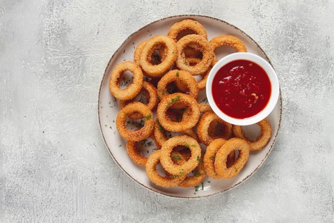 Deep fried onion rings, appetizer, with tomato sauce, on a light background, no people, favorite