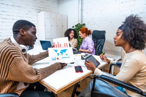 African man showing data to a disabled colleague in a modern and new coworking room