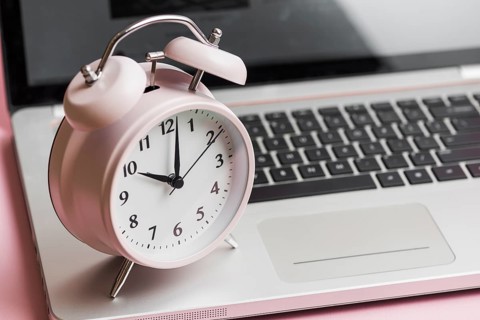 Pink vintage alarm clock open laptop