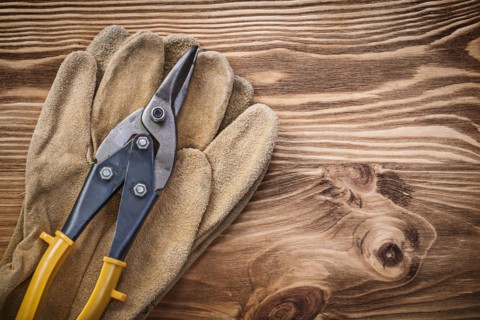 Leather protective gloves Pewter scissors on wooden board Construction concept