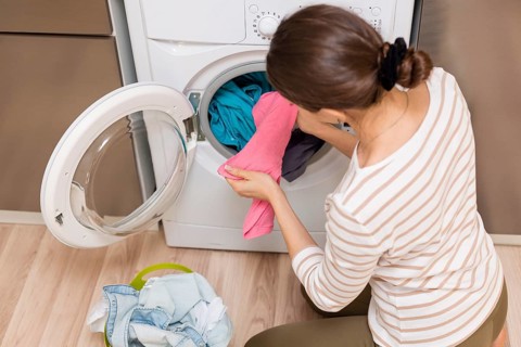 Lady taking clothes out washing machine. High resolution photo