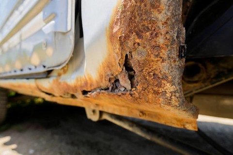 Body repair and welding work required. Rust on a gray old car. Rust hole on an old worn out painted