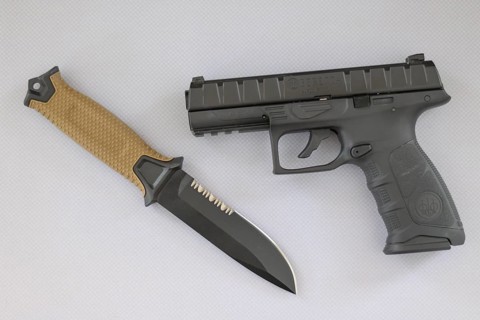 Black pistol and hunting knife with beige handle lie on a white surface