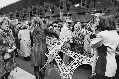 Employees carry a model of the Eiffel Tower across the pavement at the opening of the French