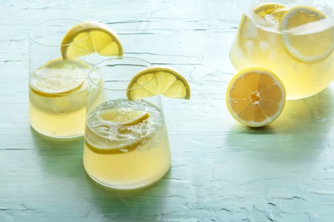 Lemonade. Lemon water drink with ice. Two glasses and a pitcher on a blue background. Detox