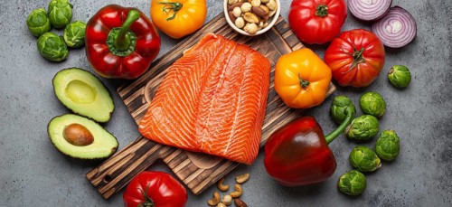 Fresh raw salmon fillet on wooden cutting board, organic bio vegetables and nuts on rustic stone