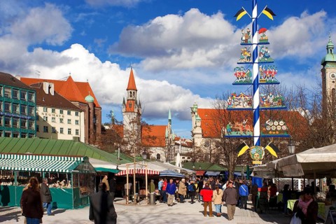 Busy food market Viktualienmarkt in February, winter, may pole in the middle ground, tower of old
