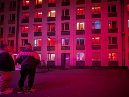 Laufhaus, clients in front of the facade of a red-lit brothel with prostitutes in the windows,