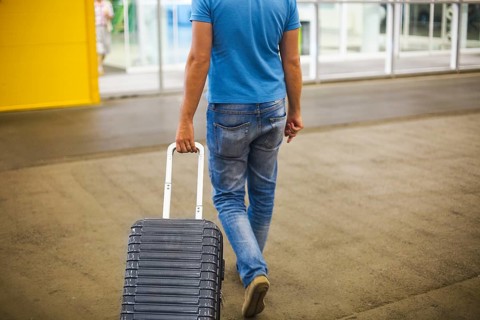 Young man with suitcase at airport or station with suitcase. Close up