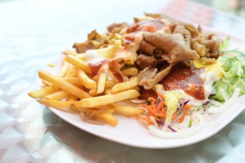 Doner kebab on a plate with French fries, salad and various sauces on a plate, popular fast food