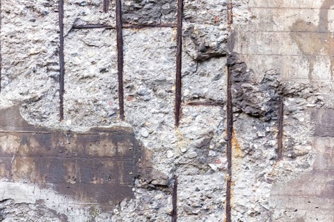 Textured concrete wall with exposed rebar and a rustic look