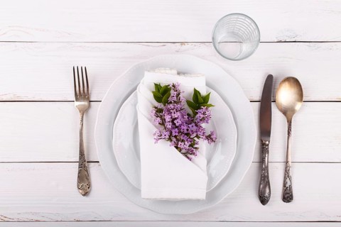 Spring festive table setting with vintage cutlery and lilac flowers on white wooden table, copy