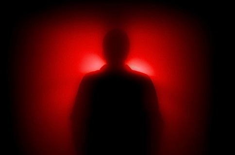A diffuse figure in the red backlight, concept image, fear, anonymity, AI generated