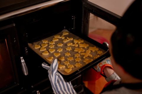 Baking tray with Christmas biscuits is placed in the oven
