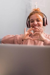 Smiley female teacher showing heart sign students during online class