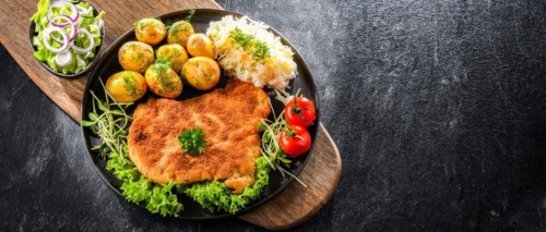 Pork breaded cutlet coated with breadcrumbs served with potatoes and cabbage