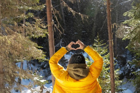 Back portrait young caucasian woman and shows fingers gesture of heart, love at eye level. Back