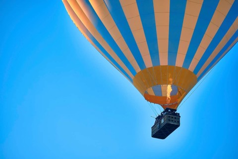 Flying hot air balloon against bright blue sky