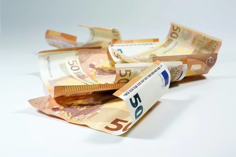 Some crumpled 50 euro bills lying randomly on a light gray background, European currency, finance