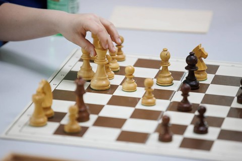 Child plays chess and moves a piece, focus on the action