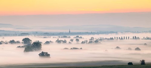 A misty landscape at sunrise with distant trees and cathedral tower, Galgenberg, Aachried,