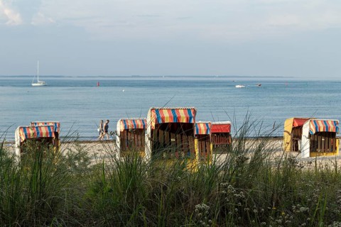 Symbolic picture weather, summer, bathers and beach chairs in the evening light on the sandy beach