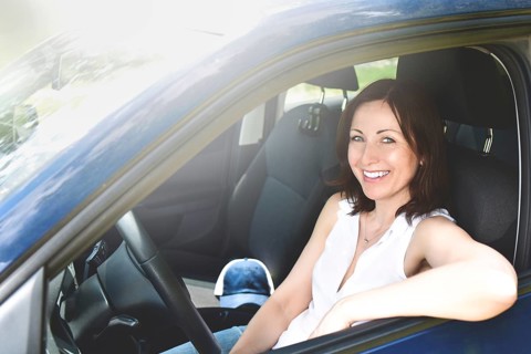 Happy adult woman driving a car and smiling. success happy brunette woman is driving a car.
