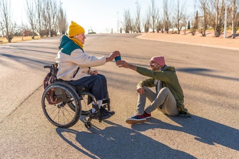 Two friends enjoying a sunny day in the park, sharing warm coffee and laughter, celebrating their