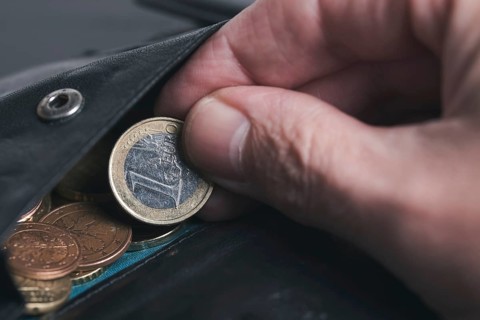 close-up of person picking 1 Euro coin from wallet, spending money business concept