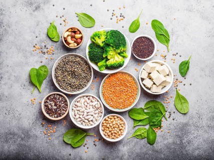 Top view of different vegan protein sources: beans, lentils, quinoa, tofu, vegetables, spinach,