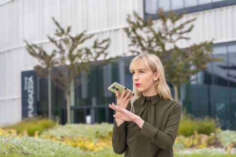Caucasian blonde entrepreneur girl in a business park sending an audio note with the phone