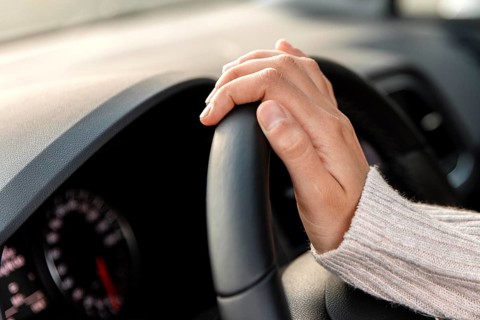 Side view woman her car holding steering wheel while driving