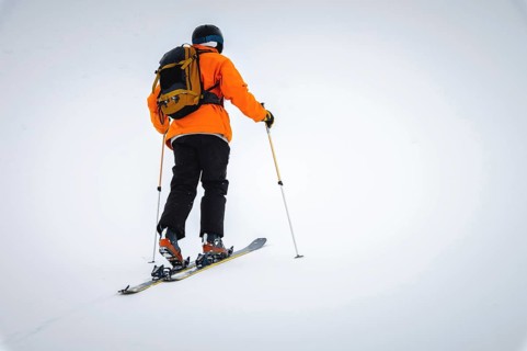A skier climbs a snow-covered ridge in the fog with a backpack, ski tour. Extreme sport in the