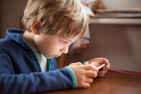Young cute boy looking aat smartphone from short distance.