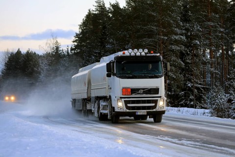 Volvo FH tanker truck transports gasoline, ADR 33-1203, on snowy highway on a winter afternoon.