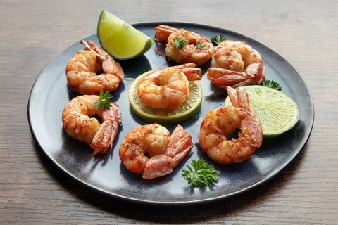 Shrimps with limes and parsley. Grilled shrimp on a rustic table. Spicy seafood appetizer