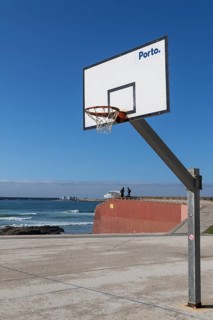 Basketball hoop in front of a blue sky with Porto lettering on the beach promenade in Matosinhos,