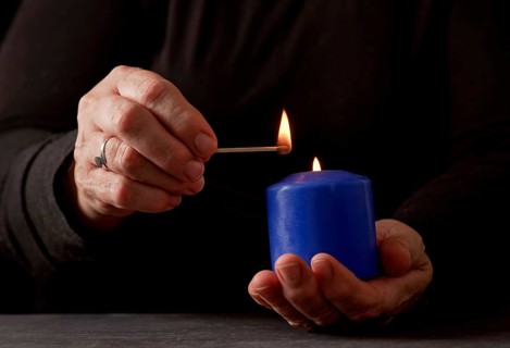 Hands of a woman lighting a blue candle with a match