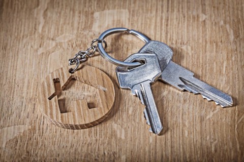 Trinket house and key on wooden background
