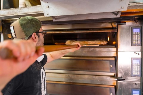 Baker of bakery in the workshop artisan workshop baking loaves in the oven