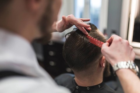 Faceless barber combing hair man before cutting