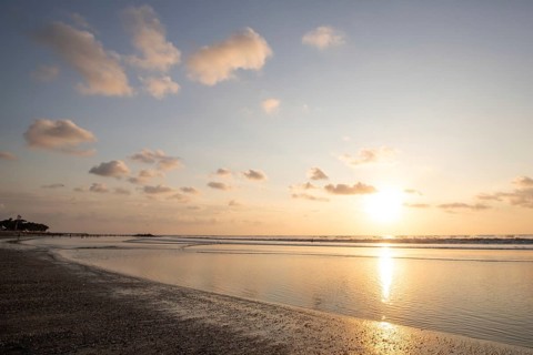 Dreamlike sunset on the dream beach of Kuta, small waves sunset over the sea and the reflection of